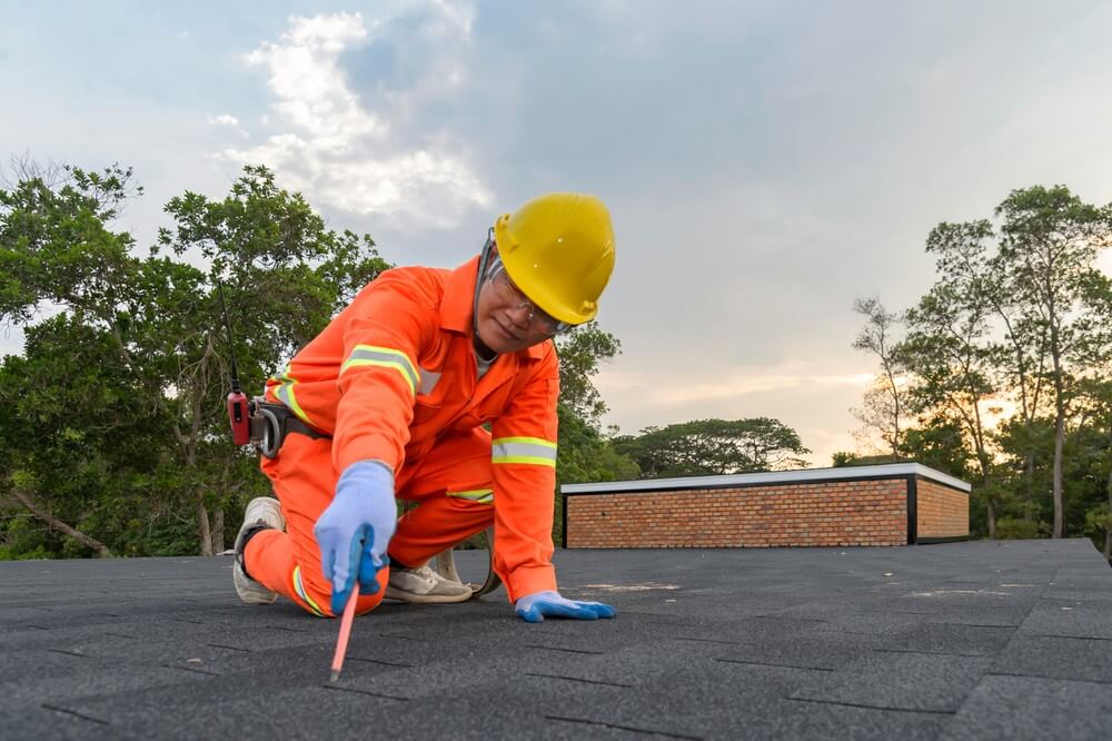 worker inspecting flat asphalt rooftop