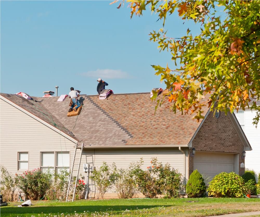 men applying new shingles to home roof