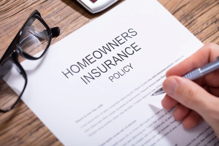 A person filling out a homeowners insurance policy form